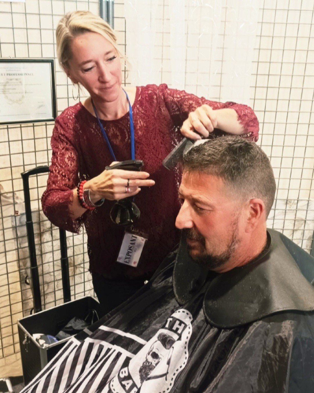 Ludivine coiffe un client, peigne et tondeuse en main